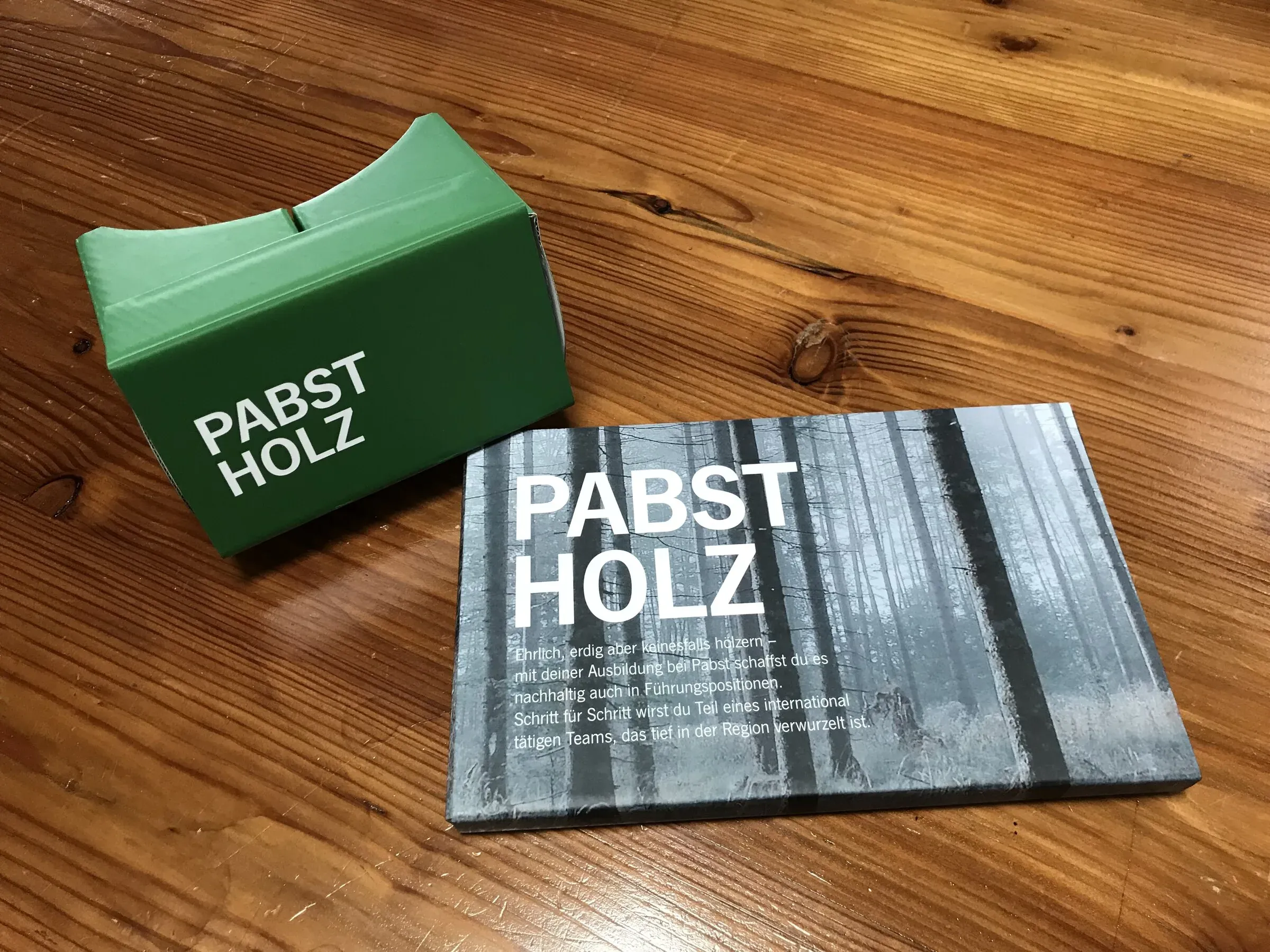 Pabst-Holz-gebrandeter Cardboard-VR-Viewer auf Holztisch mit zugehöriger Broschüre